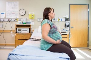 Pregnant woman sitting in hospital room waiting for prenatal care.